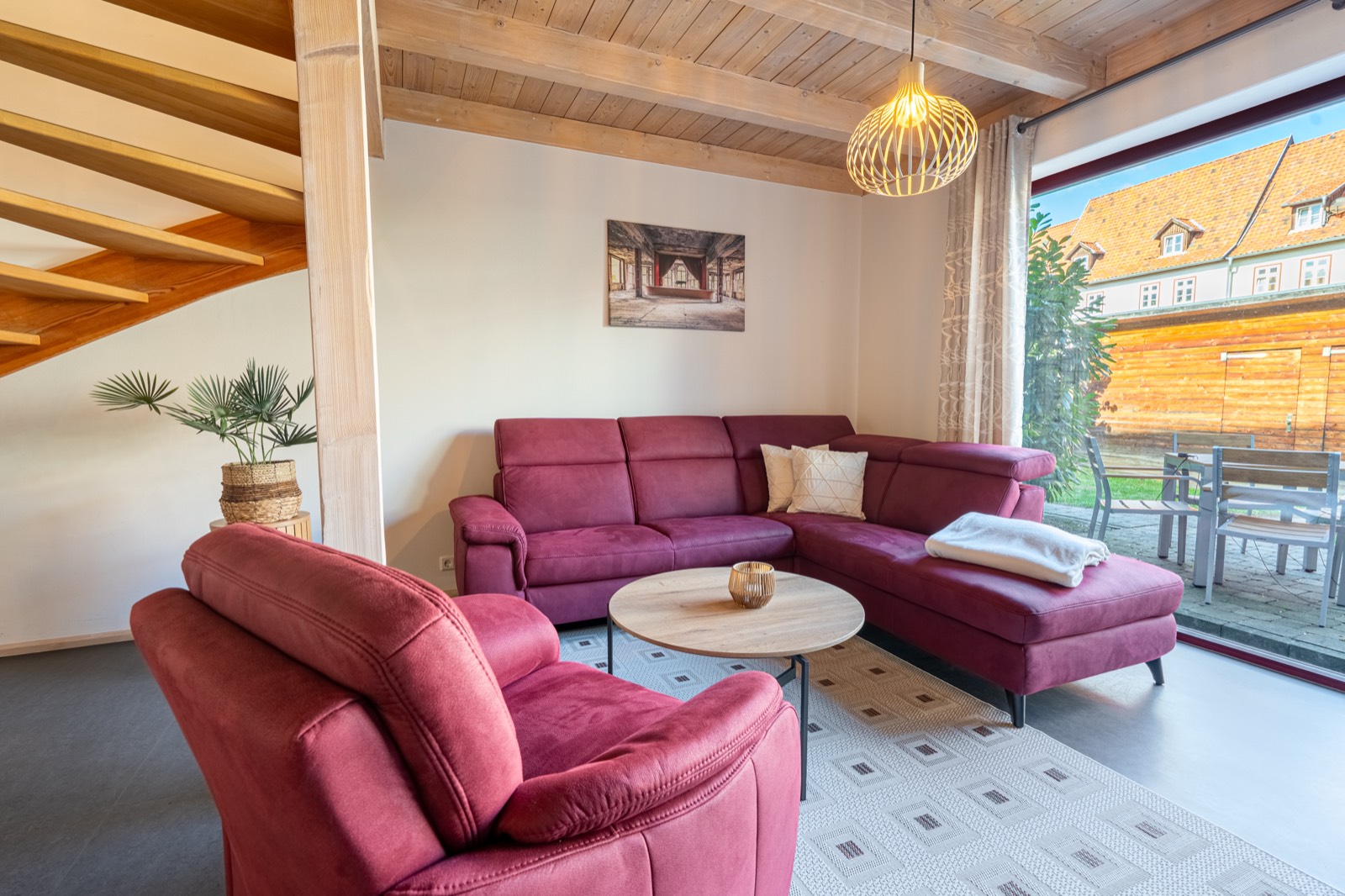 Wohnzimmer mit Ecksofa, Sessel und Holzbalkendecke